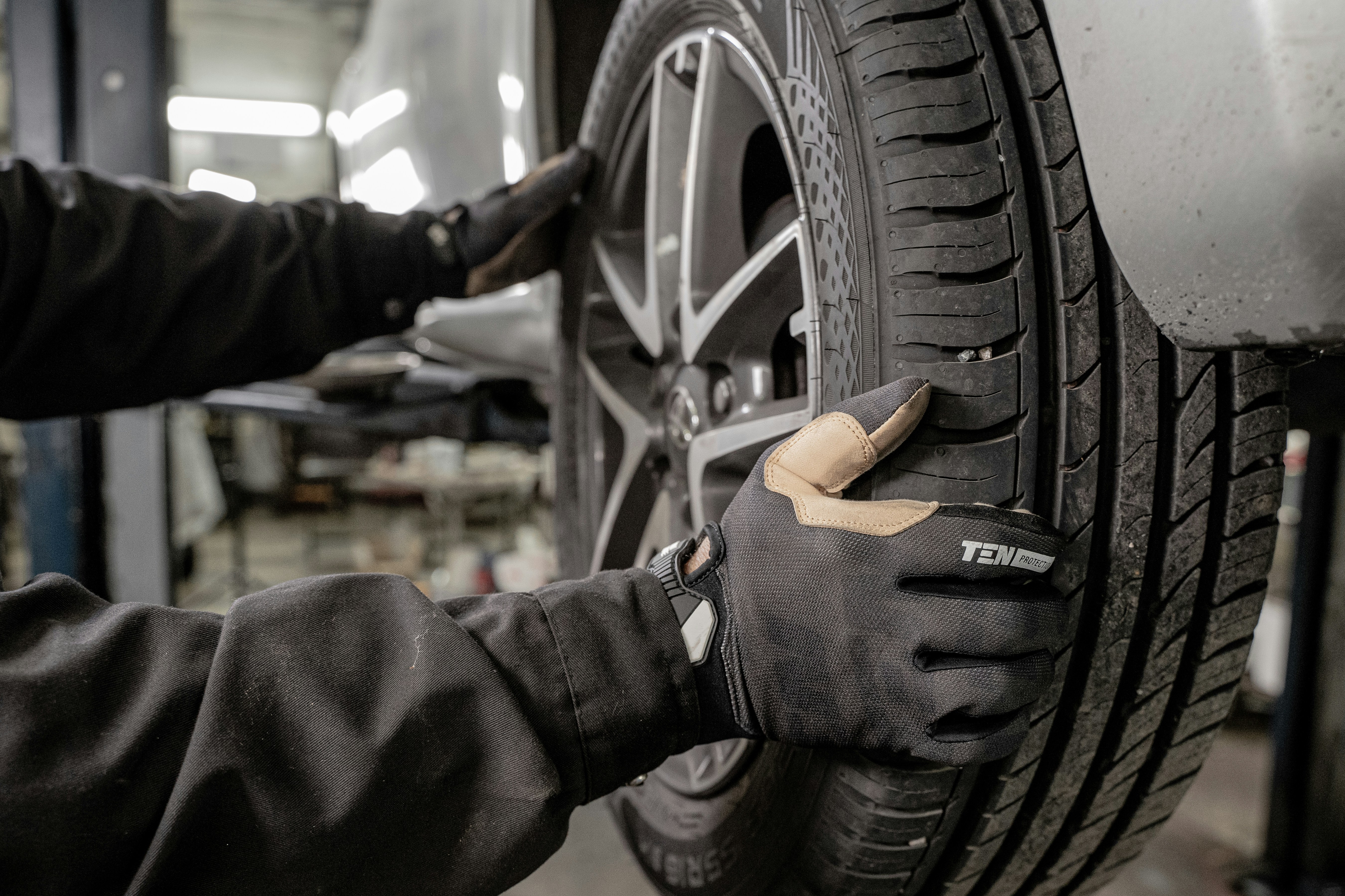 Technician's gloved hands inspecting a wheel and tire